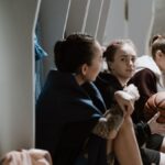 Three teenage girls sitting in a locker room, holding a basketball and chatting after practice.
