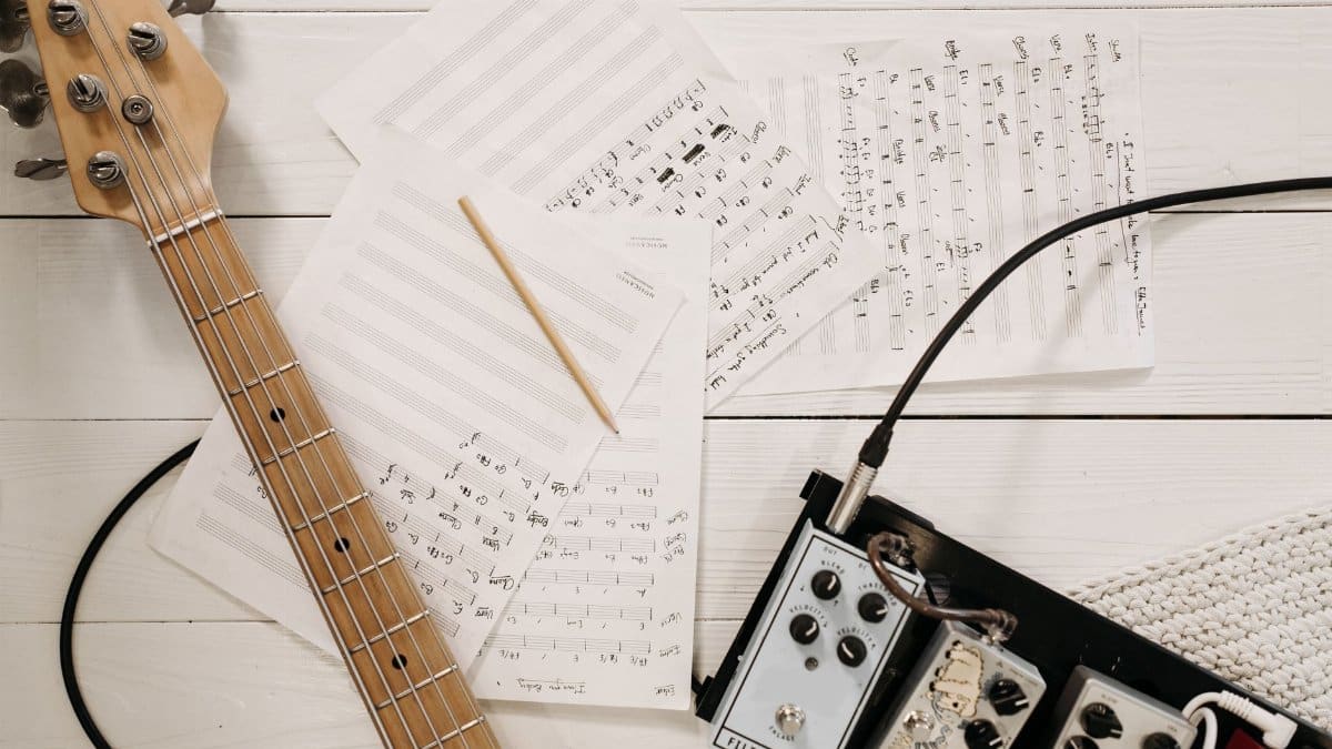 Bass guitar and music equipment arranged on a white surface, showcasing creative music setup.