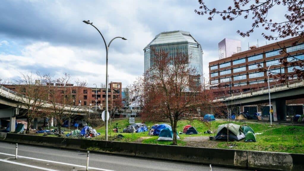 Colorful tents set up in a green area of downtown Portland, Oregon, highlight urban social issues.