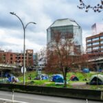 Colorful tents set up in a green area of downtown Portland, Oregon, highlight urban social issues.