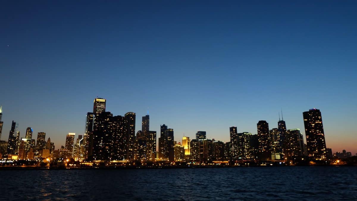 Capture of Chicago's skyline at dusk with illuminated skyscrapers reflecting on Lake Michigan.