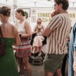 People browsing artwork at an outdoor market in Chicago, IL under a tent.
