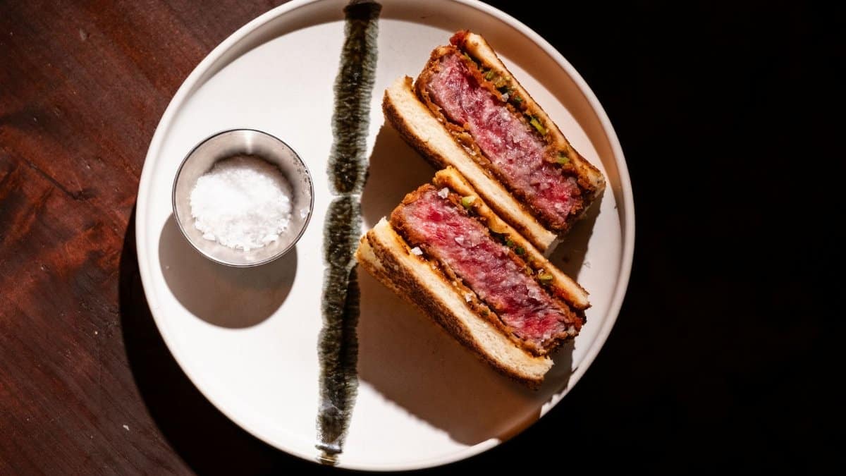 Savor a gourmet Wagyu katsu sandwich served with salt on a rustic table.