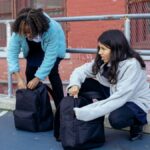 Adorable multiracial children touching backpacks while talking about education near old building of school