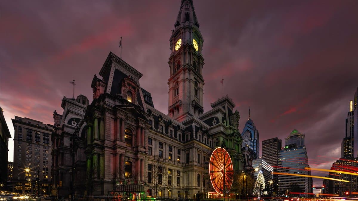 Night view of Philadelphia City Hall during Christmas with lights and a Ferris wheel.