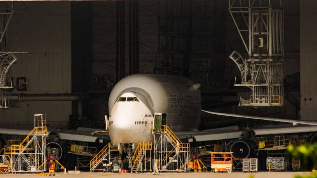A Boeing airplane undergoing maintenance in a massive aircraft hangar.