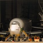 A Boeing airplane undergoing maintenance in a massive aircraft hangar.