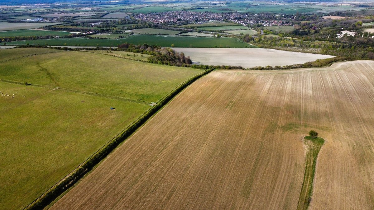Drone shot capturing the sprawling agricultural fields of Streatley, England, showcasing lush green and cultivated lands.