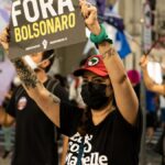 Demonstrators protesting against Bolsonaro, holding signs on a city street.