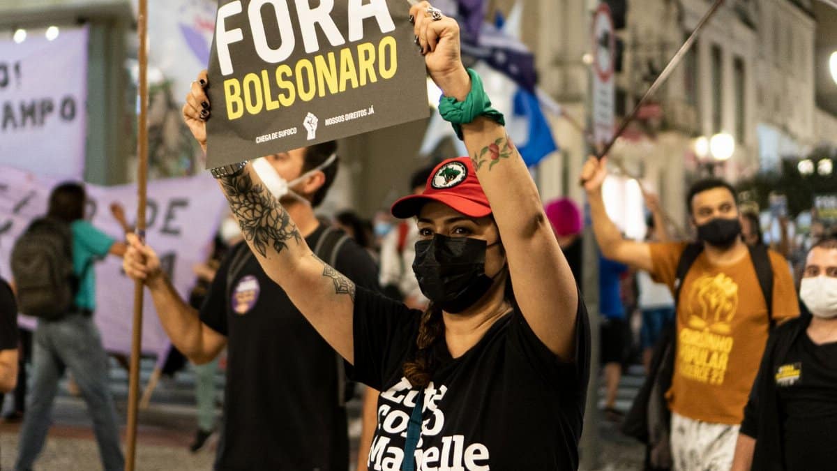 Demonstrators protesting against Bolsonaro, holding signs on a city street.