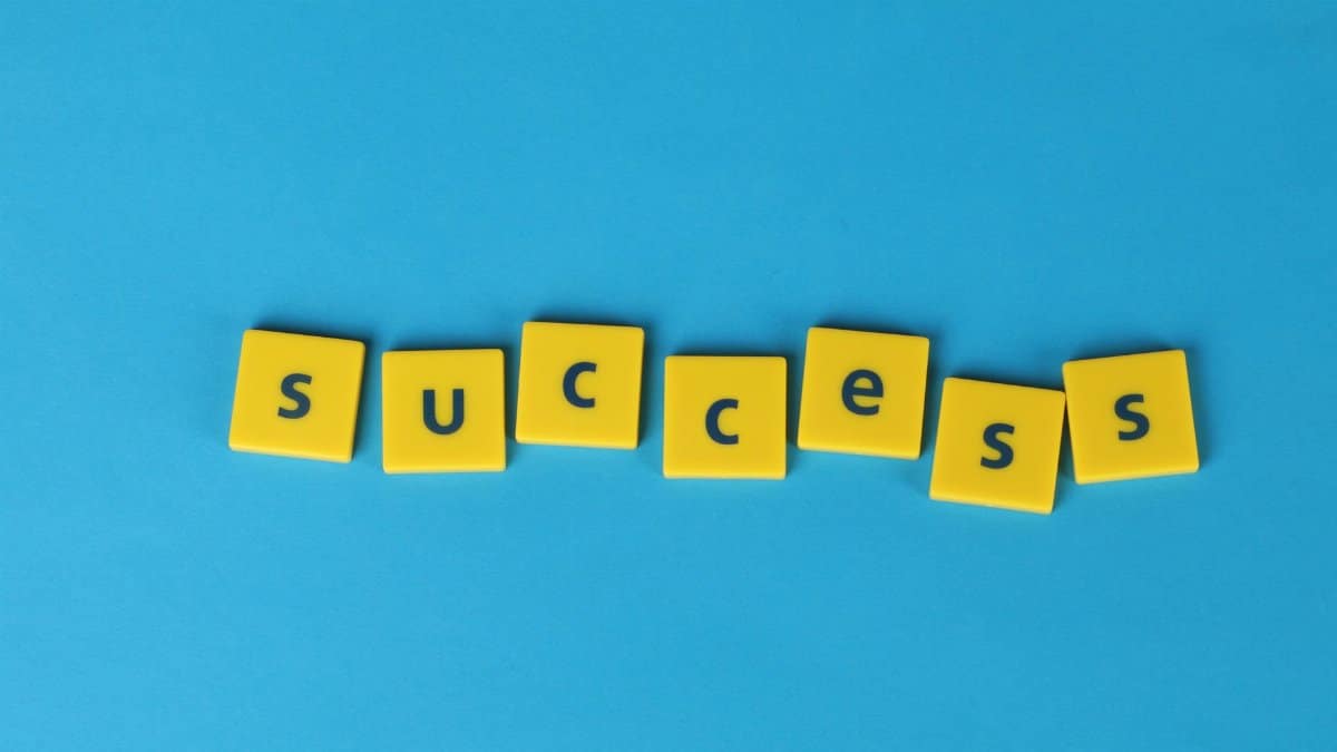 Yellow letter tiles spell the word success on a vibrant blue backdrop, symbolizing achievement.