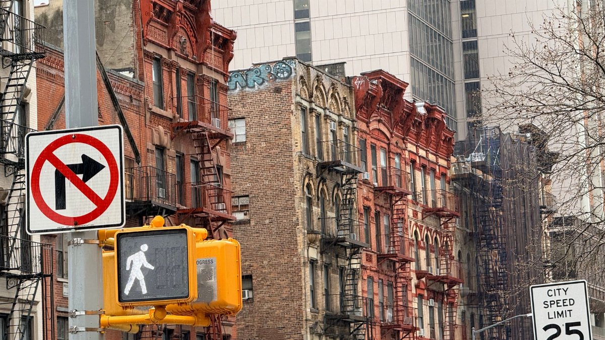 Historic New York City street with red brick brownstones and traffic signs.
