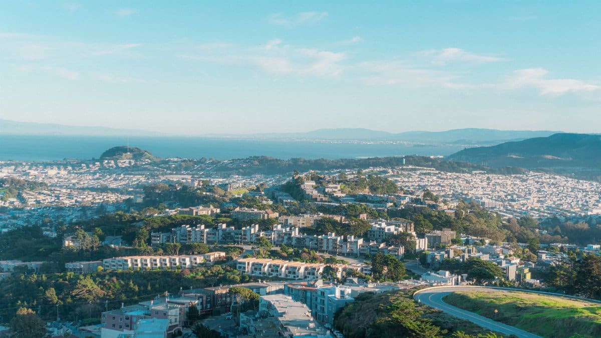 Elevated view of San Francisco's urban sprawl under a blue sky, showcasing the bay and surrounding hills.