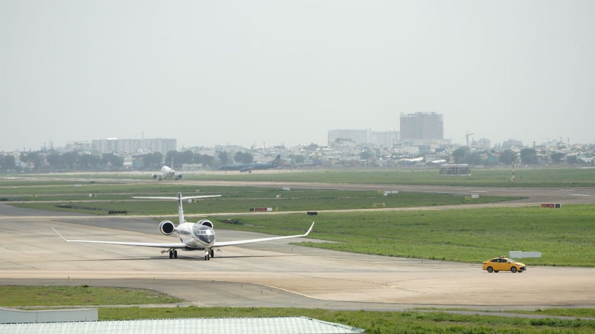 A private jet taxiing on the runway at an airport with a distant cityscape.