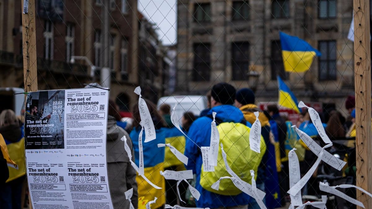 People gathered in an urban protest with Ukrainian flags waving, signifying peace and solidarity.