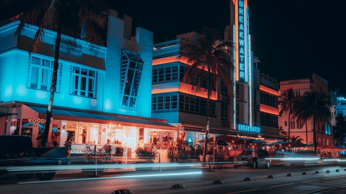 Colorful night scene of Breakwater Hotel with light trails on Miami's bustling streets.