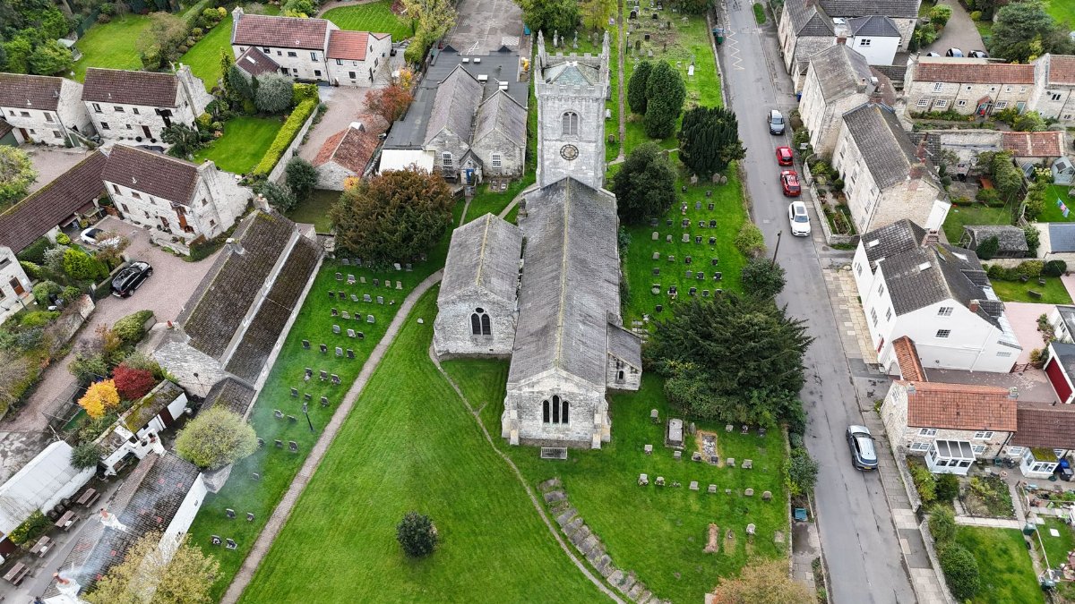 Aerial photograph showcasing the historic All Saints Church and surrounding village landscape in Saxton, England.