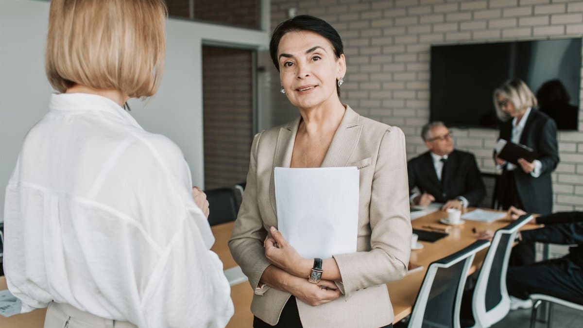 Senior businesswoman smiling and holding documents during a corporate meeting indoors.
