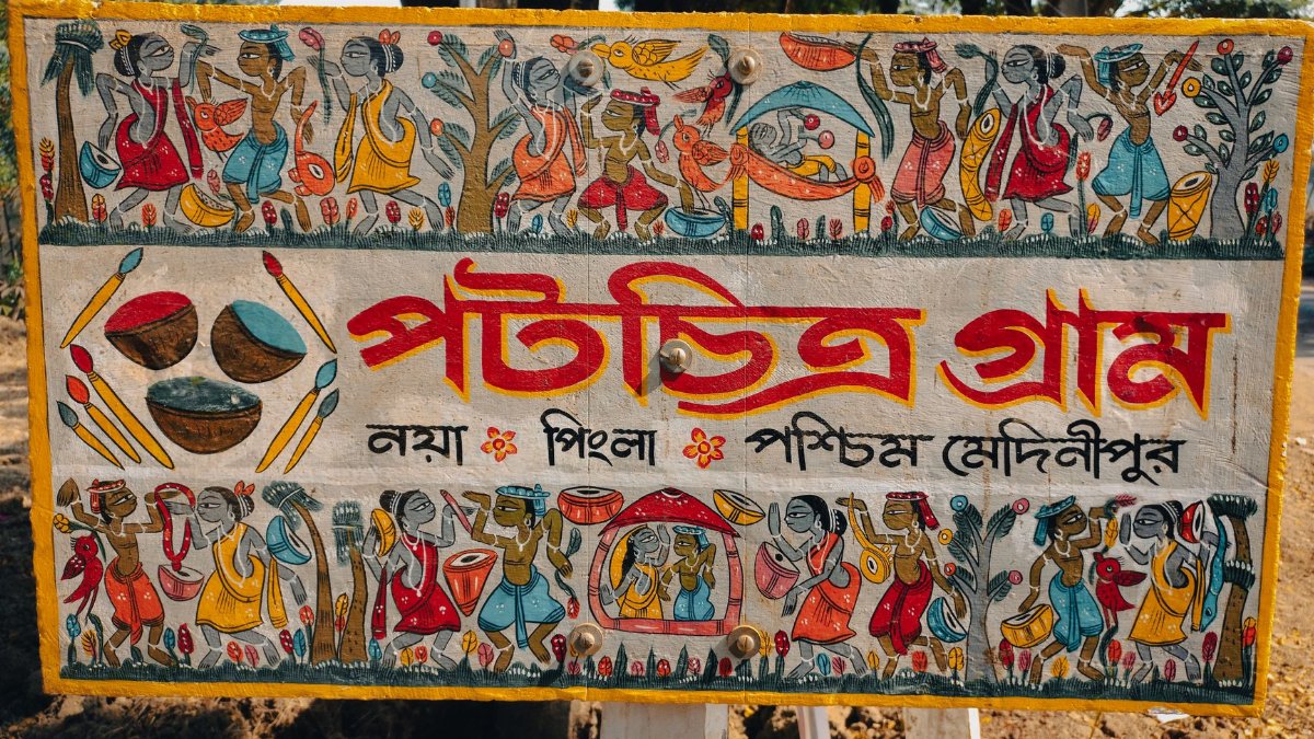 Vibrant traditional artwork showcasing folk culture on a sign in Midnapore, India.