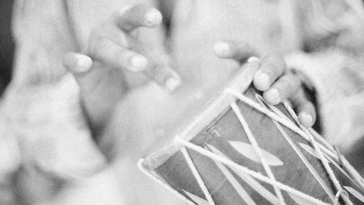Black and white close-up of hands playing a traditional drum showcasing cultural music expression.