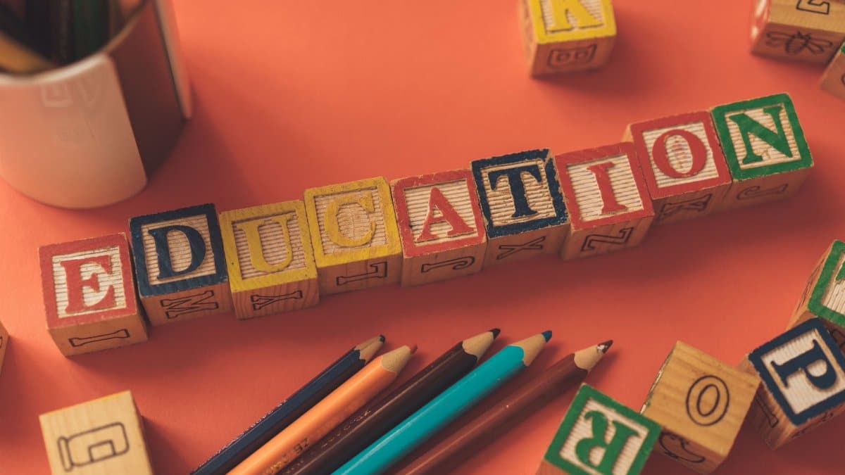 Alphabet blocks spelling 'EDUCATION' on orange background with pencils.