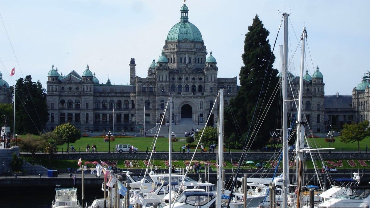 Scenic view of British Columbia's Parliament Buildings with yachts in the harbor.