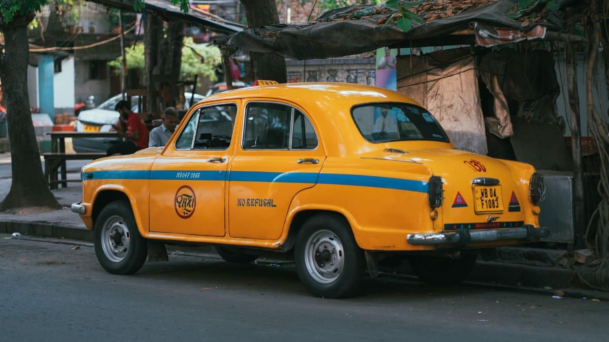 Vintage yellow taxi parked on a street corner in Kolkata, India, capturing a slice of local life.
