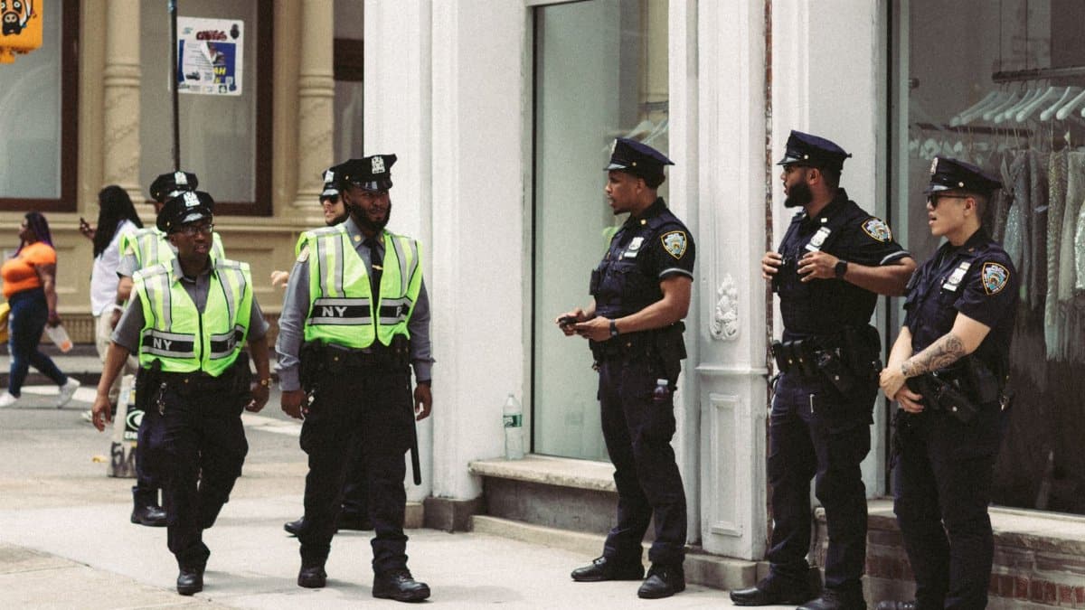 NYPD officers in uniform monitor a busy city street in daytime, ensuring public safety.