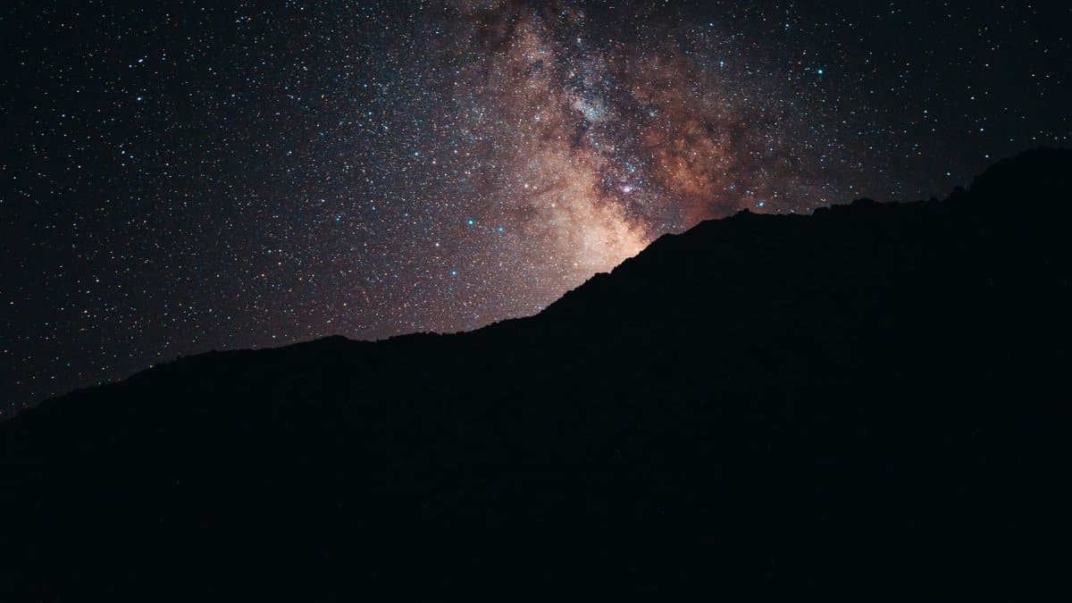 Beautiful view of the Milky Way galaxy over a mountain silhouette under a starry night sky.