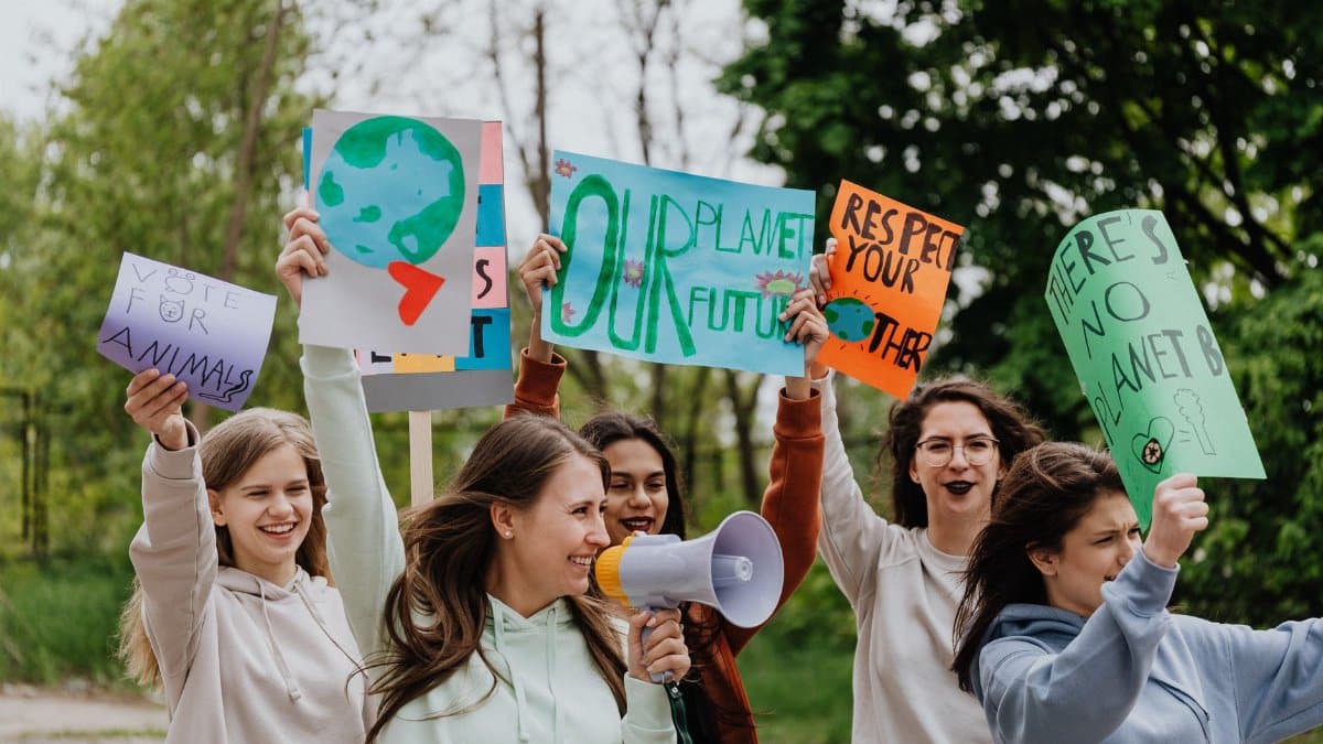 Group of young activists holding placards and megaphone during an outdoor environmental protest.