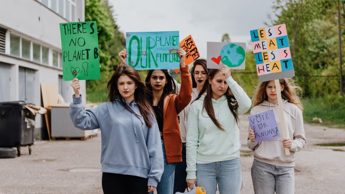 Group of women holding environmental protest signs outdoors advocating for climate action.