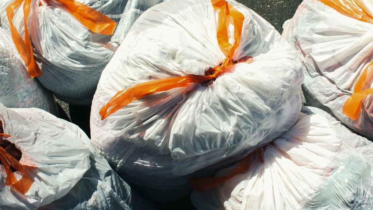 Bags of waste sealed with orange ties viewed from above.