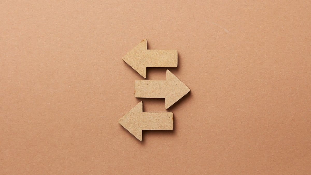 Close-up of three wooden arrows pointing in opposite directions on a beige surface.