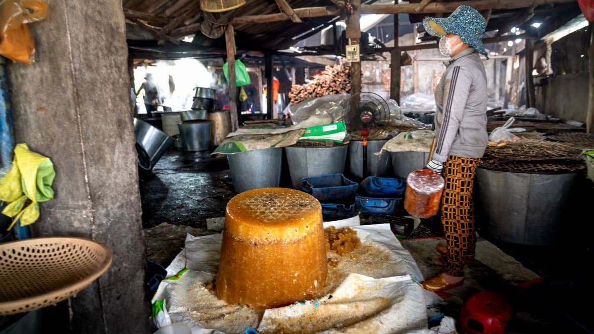 Woman in a village market producing traditional sugar indoors.