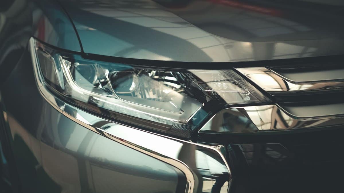 Detailed close-up of a modern car headlight with sleek chrome finish, emphasizing design and technology.