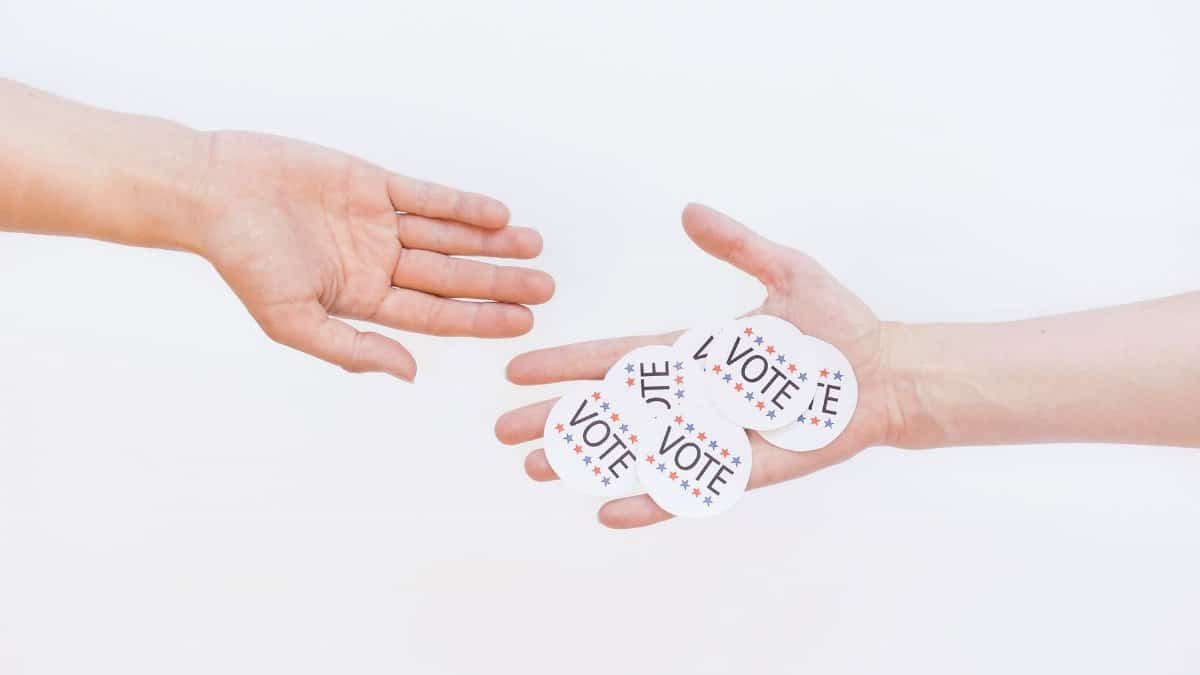 Close-up of hands exchanging vote stickers, symbolizing engagement in democratic election.