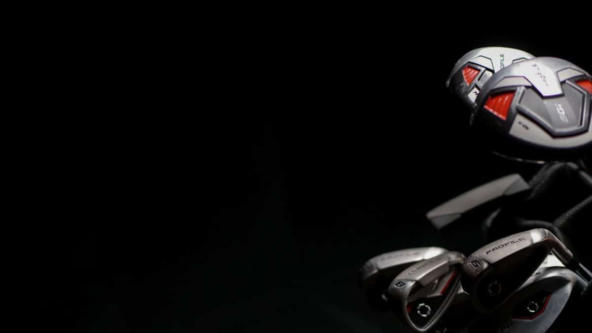 Artistic close-up image of modern golf clubs with dramatic lighting on the club heads.
