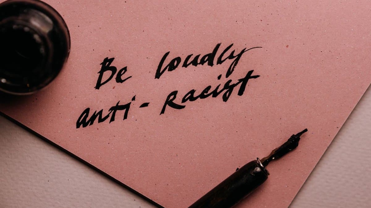 A powerful message on a pink surface promoting anti-racism with elegant calligraphy.