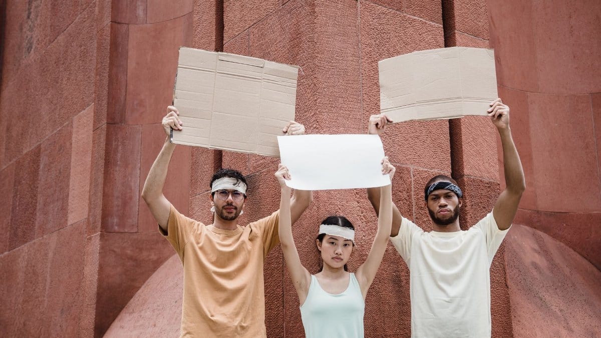 Young adults holding blank protest signs outdoors, ready for demonstration.