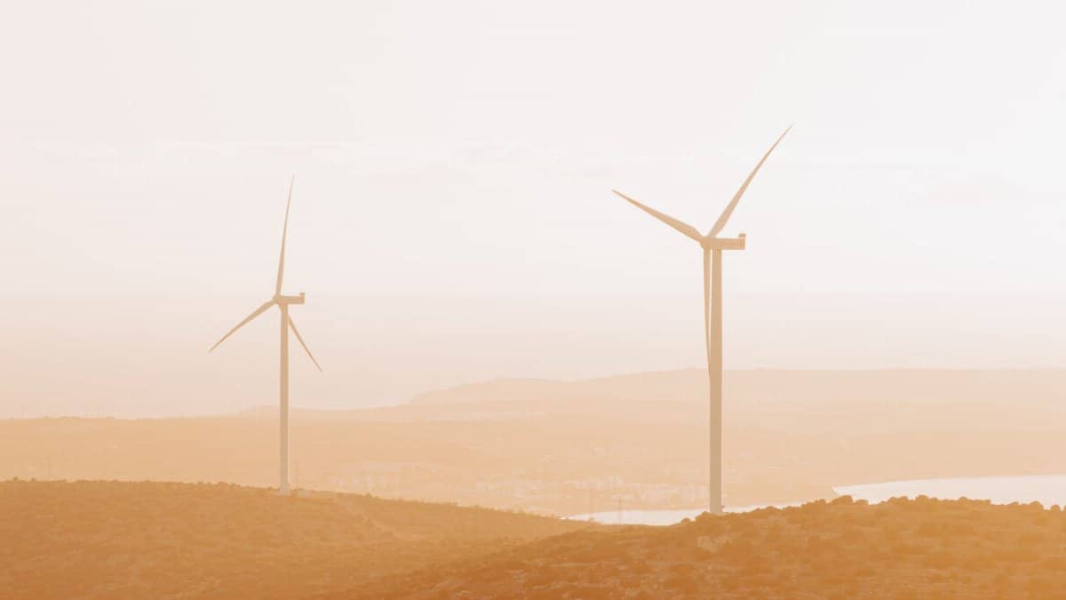 Aerial view of wind turbines on hills during sunset in Çeşme, Türkiye, showcasing renewable energy.