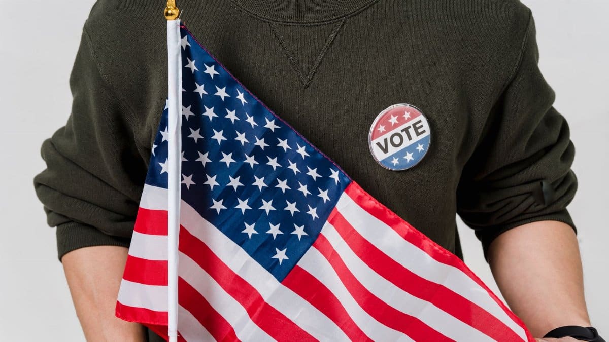 A person holding an American flag with a vote badge, symbolizing patriotism and democracy.