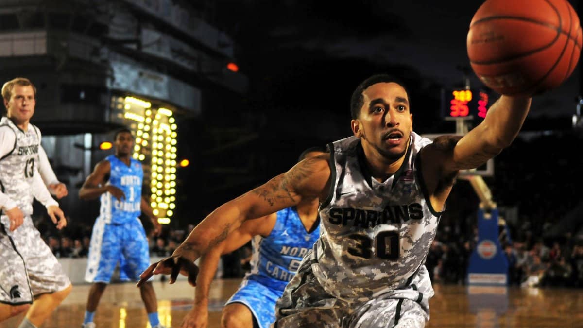 Intense basketball game with athletes in action on an outdoor court during nighttime.