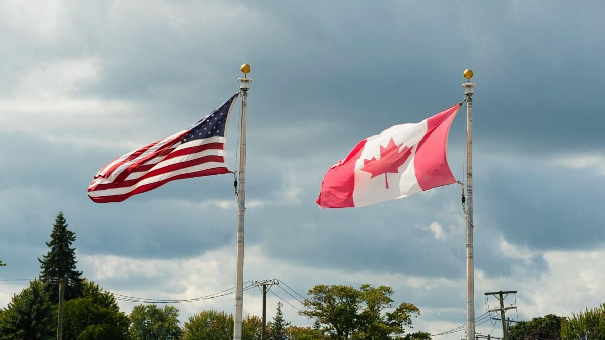 Canadian and American flags waving under a cloudy sky in Harbor Beach, MI.