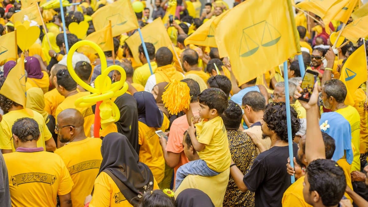 Crowd gathering with yellow flags at a political rally in Maldives, showcasing unity and enthusiasm.
