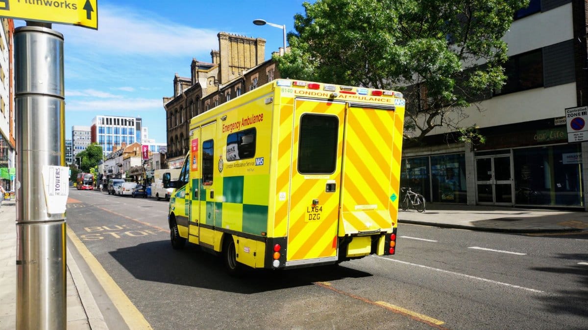 A London emergency ambulance driving through a city street in England, showcasing public health service.