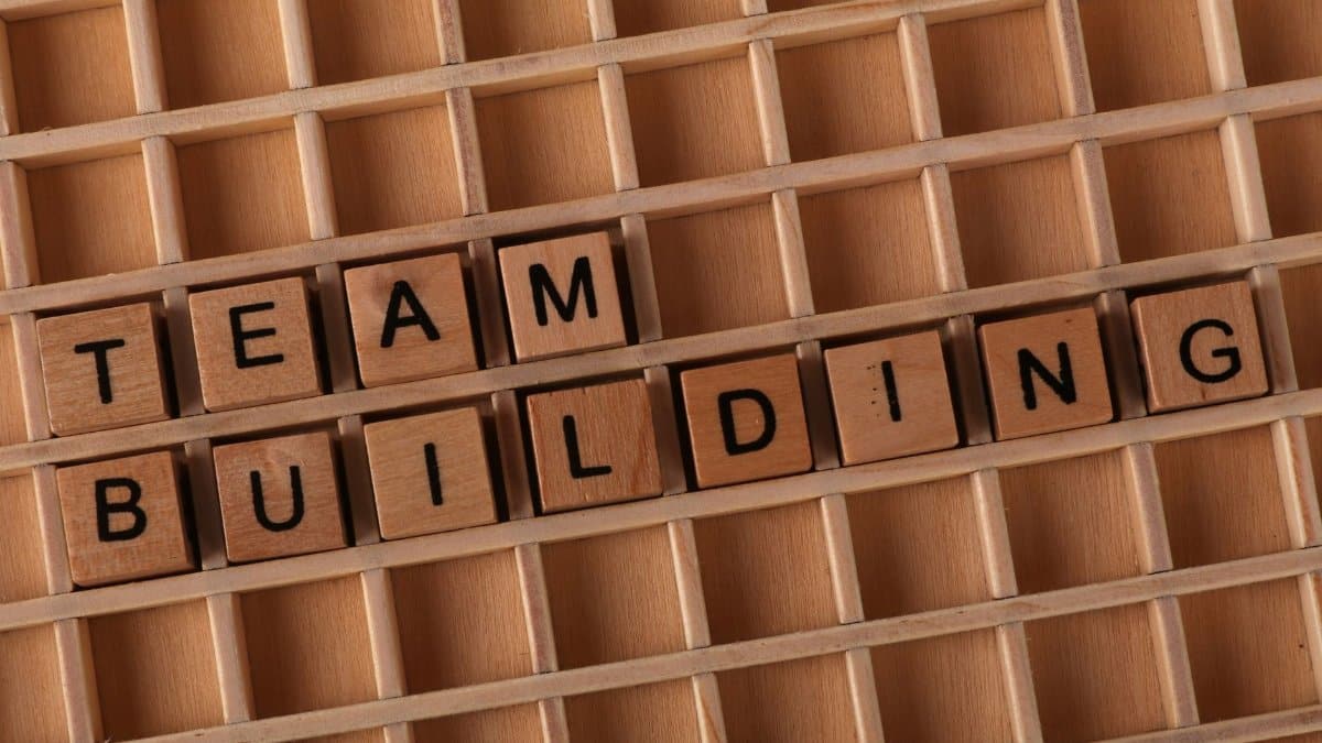 Scrabble letters spelling 'TEAM BUILDING' on a wooden board symbolize teamwork and collaboration.