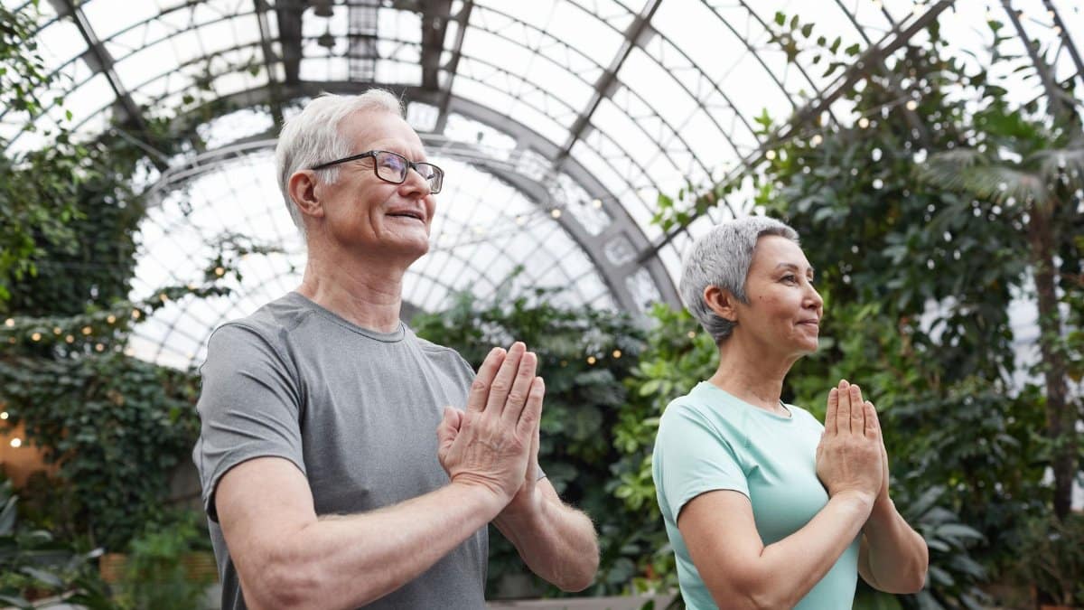 Senior couple enjoying a yoga session indoors, promoting harmony and healthy lifestyle.
