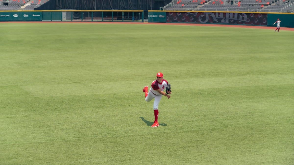 A baseball player pitching on a grass field in an empty stadium.