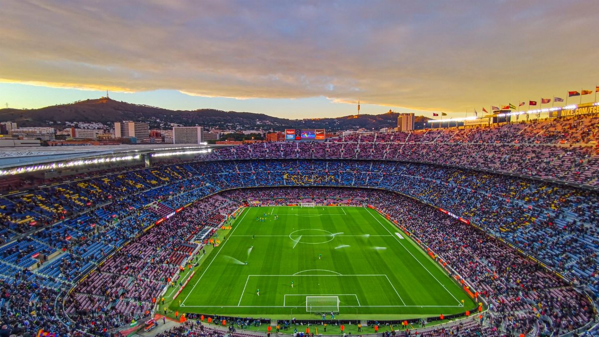Aerial view of Camp Nou stadium filled with spectators during a football match at sunset in Barcelona, Spain.