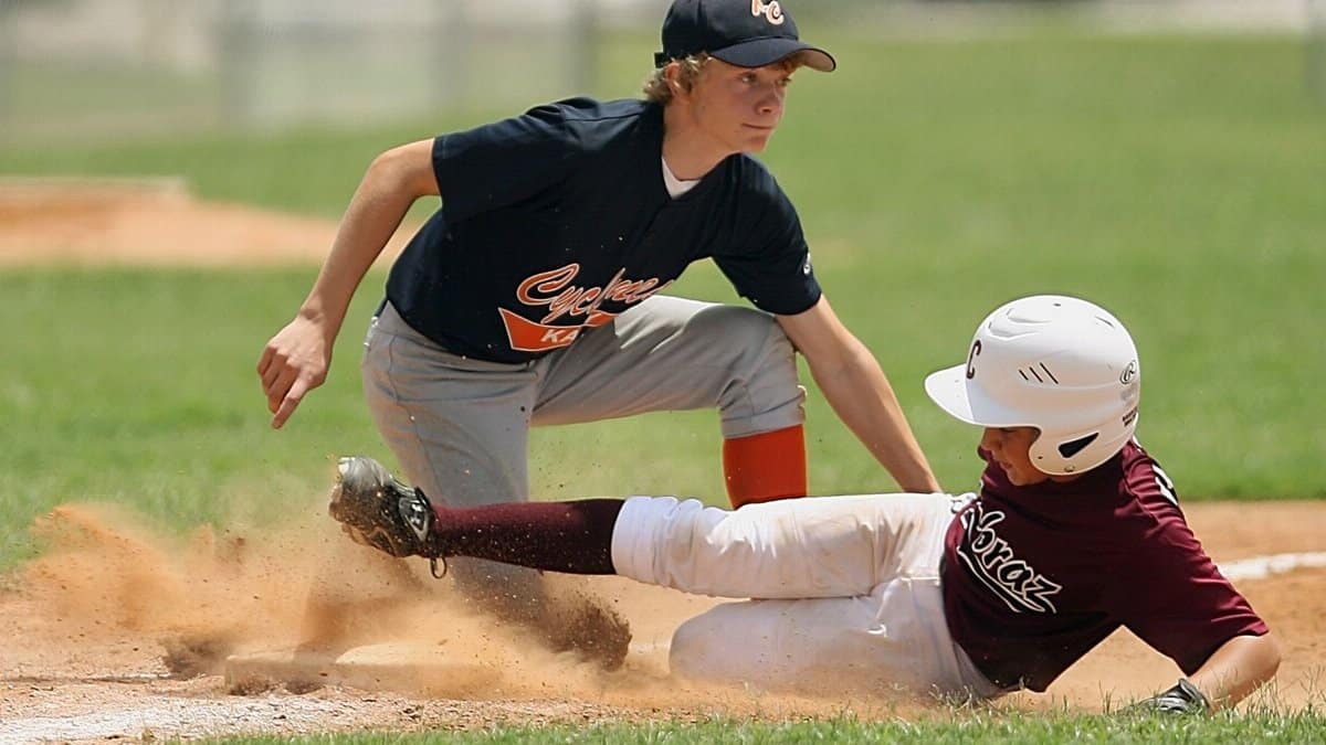 Exciting moment of young players sliding and tagging in a youth baseball game.